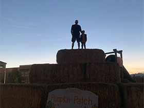 Marcy's husband and son standing on haystack in the distance.